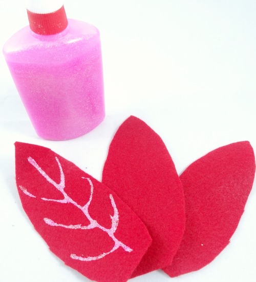 Use pink glitter glue for the veins of your poinsettia ornament